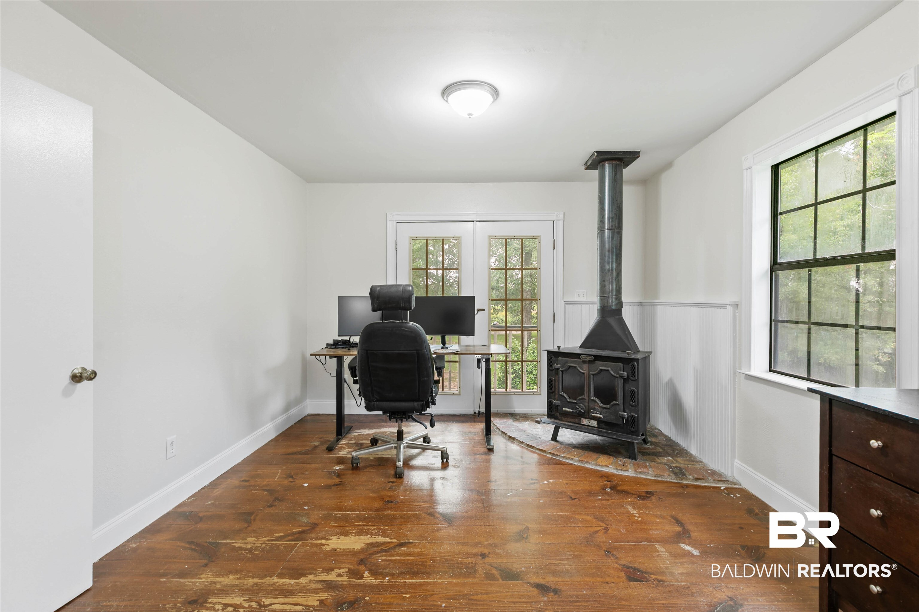 10420 Johnson Road South Mobile, AL 36695 - Photo 44 of 75 Room featuring wood-finish flooring, a freestanding solid fuel stove with a metal flue, and a board and batten wall treatment