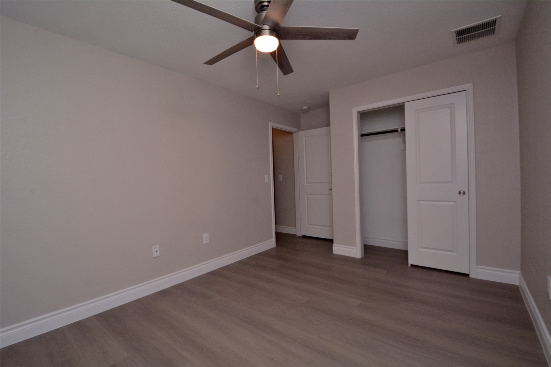 3901 Colorado High Avenue Austin, TX 78744 - Photo 22 of 39 an empty room with wooden floor ceiling fan and window