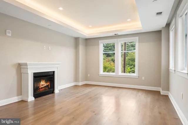 a view of an empty room with wooden floor fireplace and a window