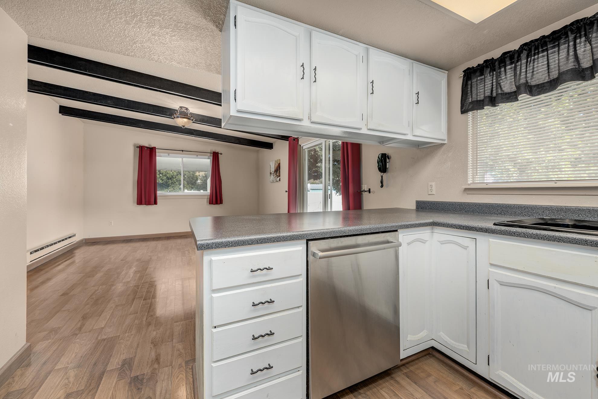 885 Airport Road Vale, OR 97918 - Photo 11 of 36 Kitchen with white cabinets, a peninsula, stainless steel dishwasher, light wood finished floors, and a textured ceiling