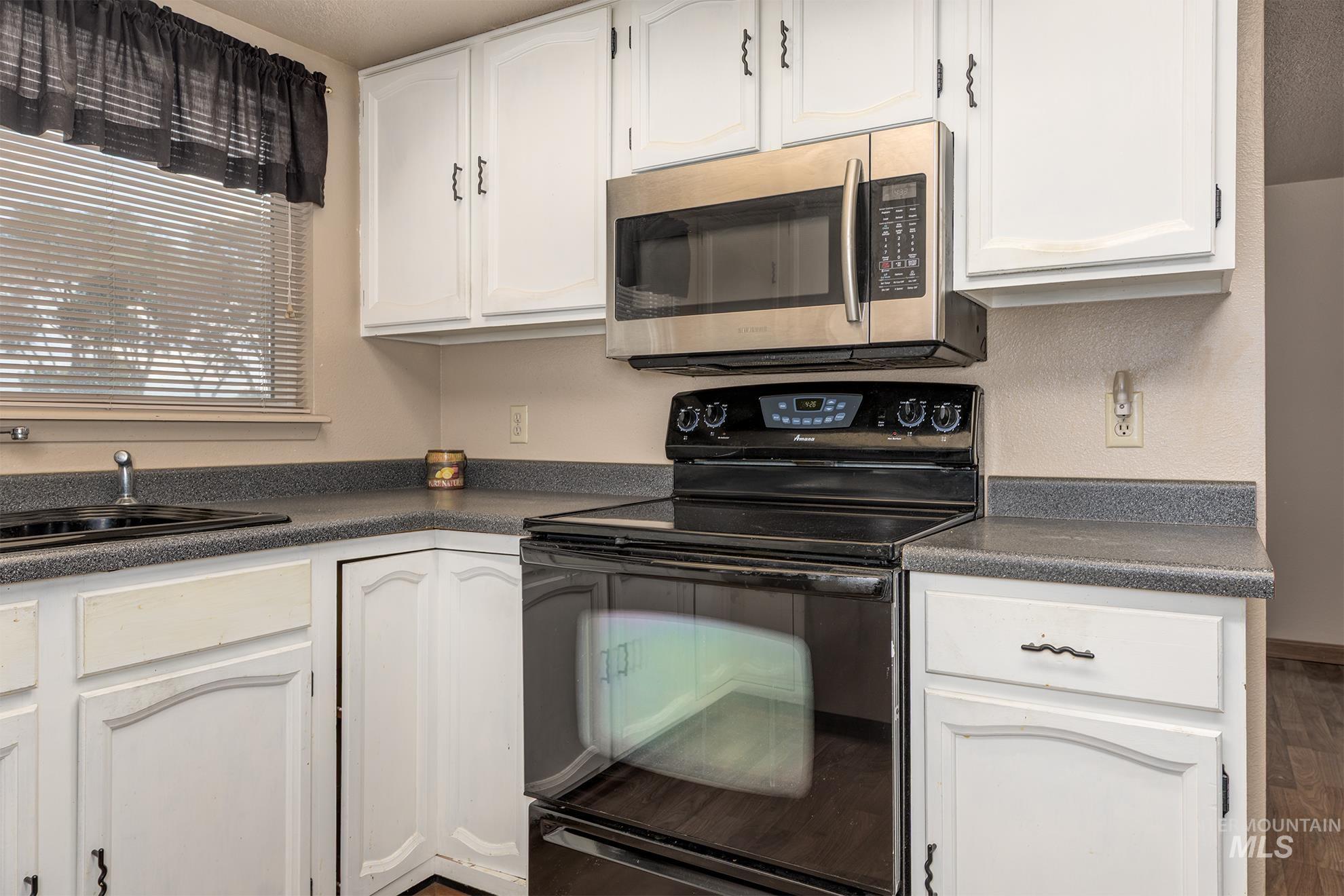 885 Airport Road Vale, OR 97918 - Photo 9 of 36 Kitchen featuring black range, dark countertops, stainless steel microwave, and white cabinetry