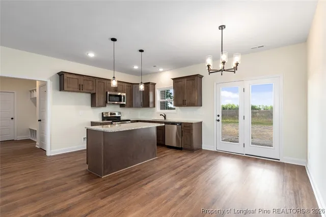 a kitchen with stainless steel appliances kitchen island granite countertop wooden floors and a sink