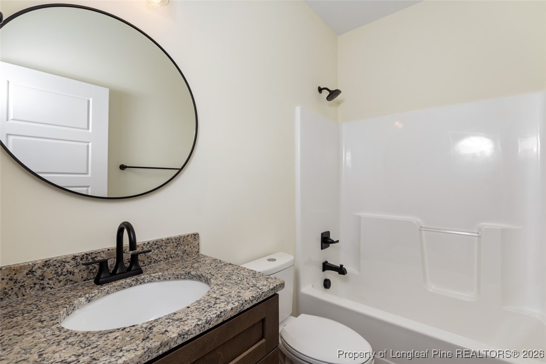 195 Barberry Road Raeford, NC 28376 - Photo 25 of 30 a bathroom with a granite countertop sink toilet and a mirror