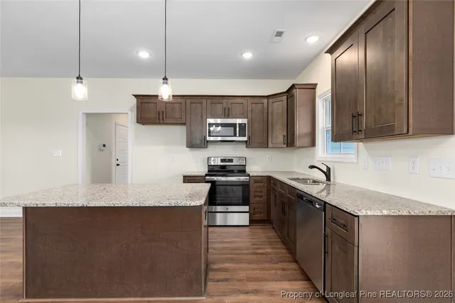 a large kitchen with stainless steel appliances granite countertop a sink a stove and a refrigerator