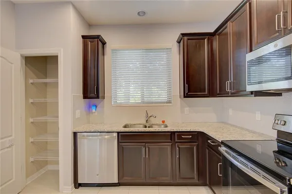a kitchen with granite countertop a sink cabinets and stainless steel appliances