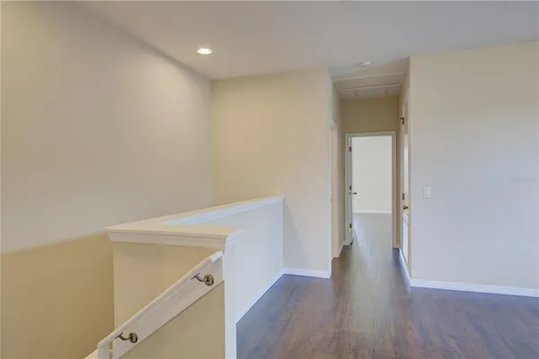 an empty room with wooden floor and a ceiling fan
