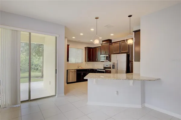 a large kitchen with kitchen island a large counter top stainless steel appliances and cabinets