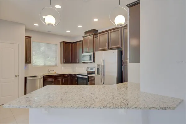 a kitchen with stainless steel appliances granite countertop a refrigerator a sink a stove and a microwave