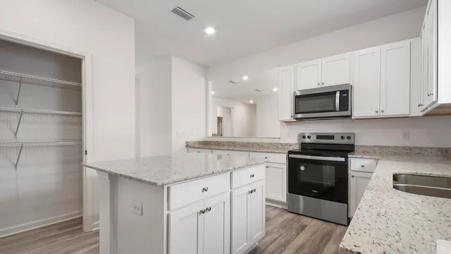 a kitchen with stainless steel appliances granite countertop a stove a sink and a microwave