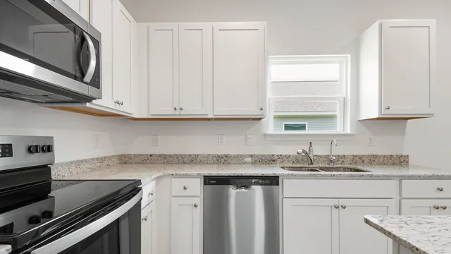 a kitchen with granite countertop a sink stove and cabinets