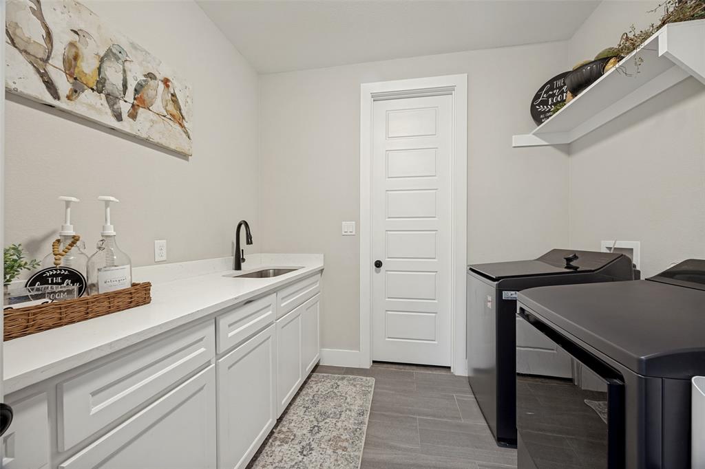 1105 Ranch Drive Bonham, TX 75418 - Photo 16 of 25 Dedicated laundry space featuring a white paneled door that leads into the primary suite closet, gray tile flooring, and a granite countertop with an undermount sink