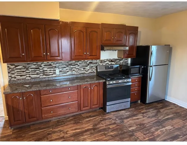 a kitchen with stainless steel appliances granite countertop a stove refrigerator and cabinets
