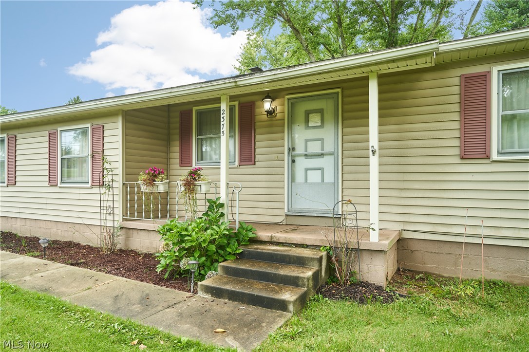 2375 Killian Road Akron, OH 44312 - Photo 3 of 19 Front exterior featuring light-colored siding, red window shutters, and a covered porch with concrete steps