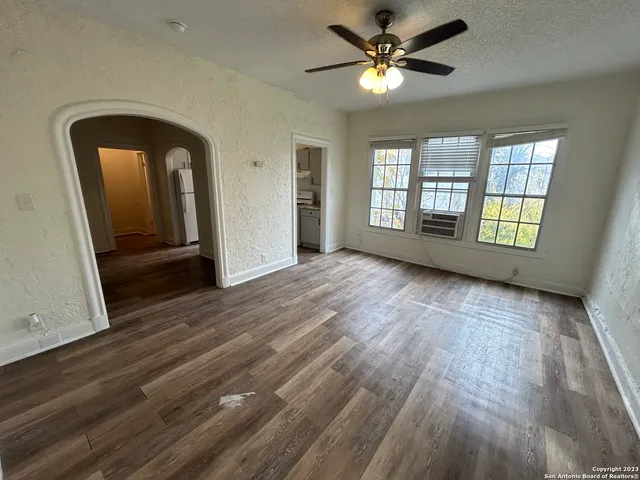 a view of empty room with wooden floor and fan