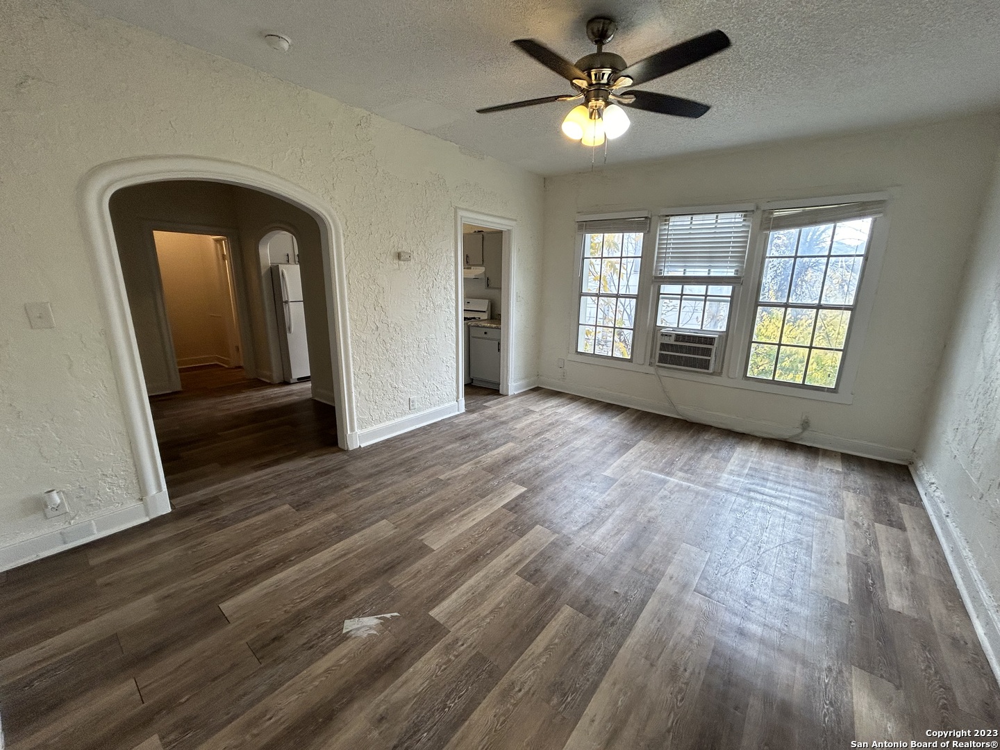 a view of empty room with wooden floor and fan