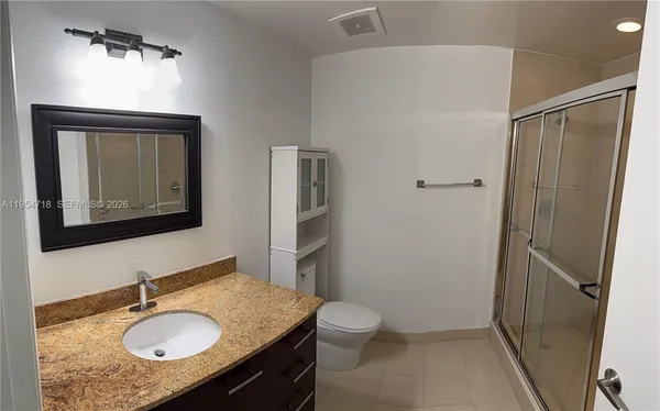 a bathroom with a granite countertop sink toilet and shower