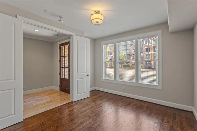 a view of an empty room with wooden floor and a window