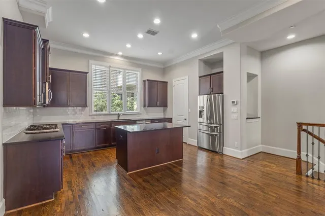 a kitchen with stainless steel appliances granite countertop a refrigerator a sink dishwasher a stove with wooden floors and cabinets