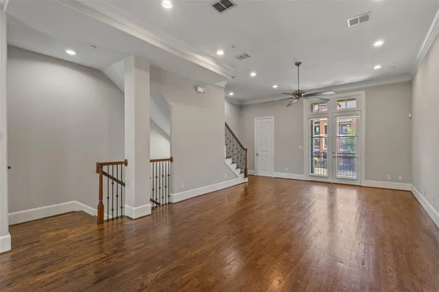 a view of an empty room with wooden floor and stairs