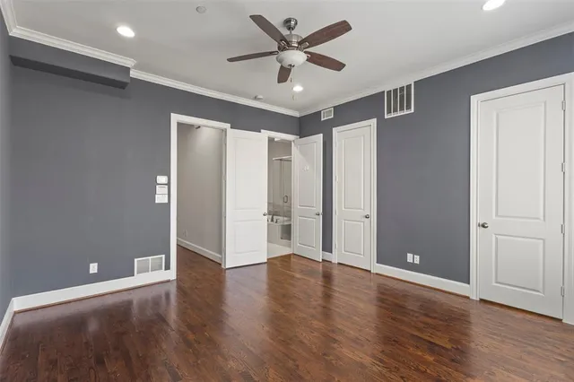 an empty room with wooden floor and a ceiling fan