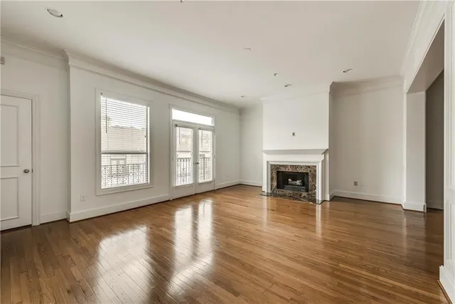 a view of a big room with wooden floor fire place and windows