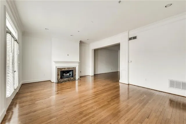 an empty room with wooden floor fireplace and windows