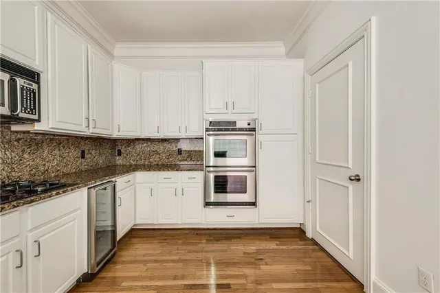 a kitchen with stainless steel appliances granite countertop a stove and white cabinets