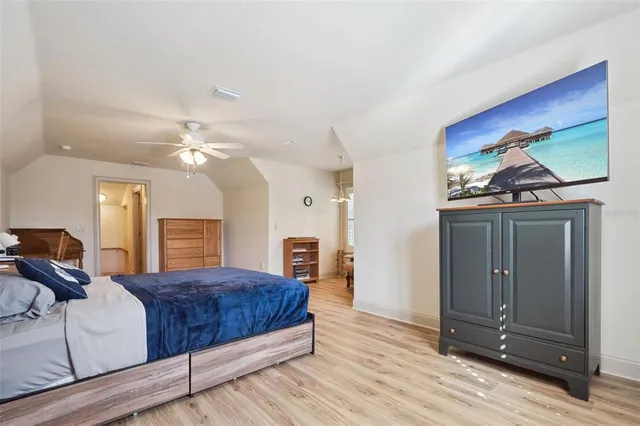 a bedroom with a bed and dresser with wooden floor