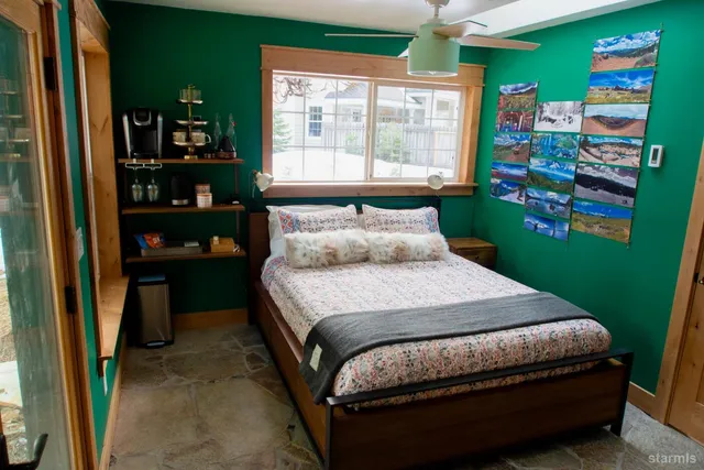 a bedroom with a bed bookshelf and a large window