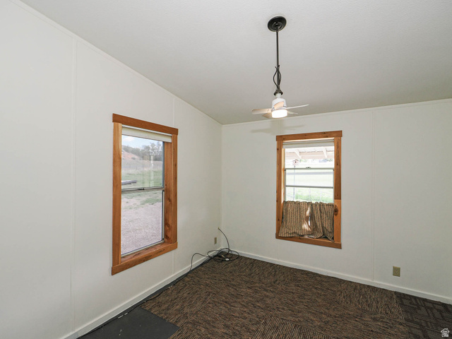 94 Spring Canyon Road Coalville, UT 84017 - Photo 32 of 50 Room featuring two windows with wood-finish trim, a ceiling fan with integrated lighting, and textured carpet flooring
