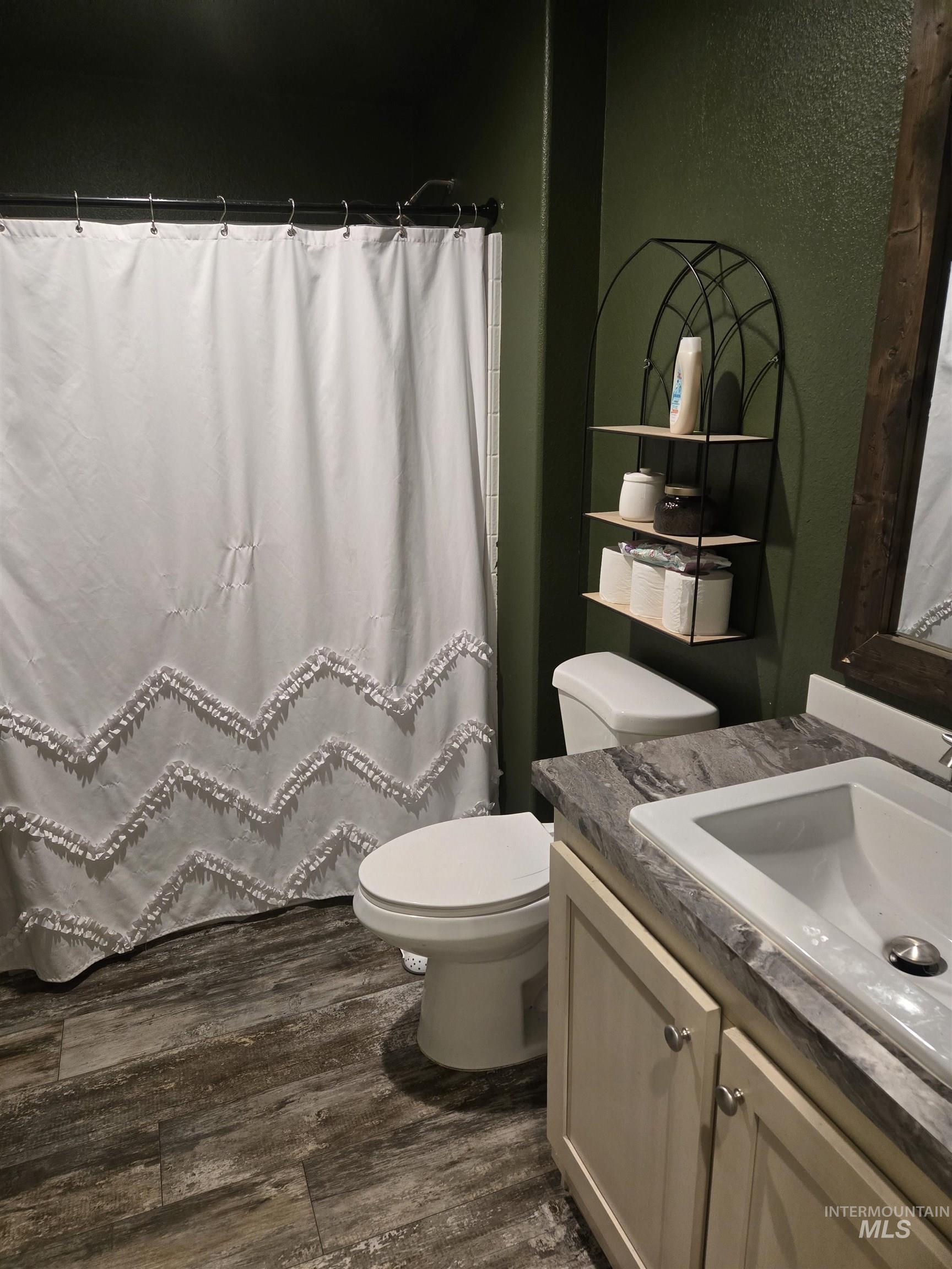 174 Konkolville Road Orofino, ID 83544 - Photo 23 of 43 Bathroom featuring wood-finish flooring, a white vanity with a recessed sink, a patterned countertop, and a built-in wall shelf