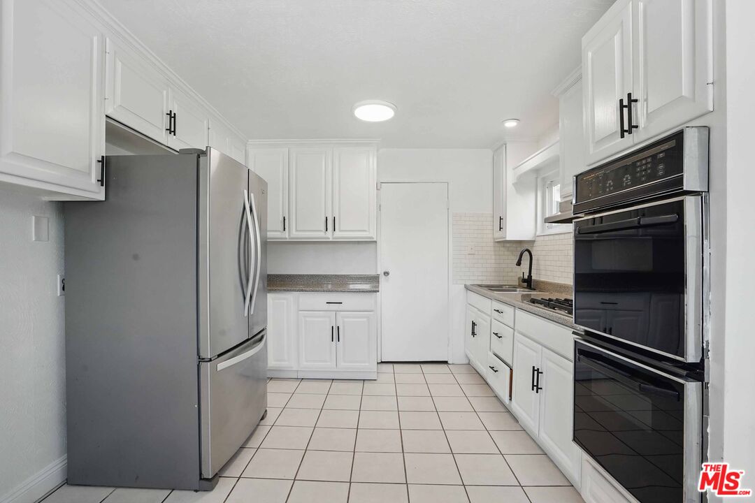 2108 Hauser Boulevard Los Angeles, CA 90016 - Photo 6 of 23 a kitchen with stainless steel appliances a refrigerator sink and cabinets