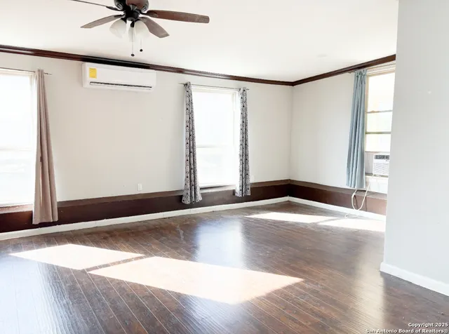 an empty room with wooden floor and windows