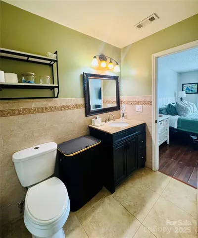 a bathroom with a toilet sink vanity granite and a mirror