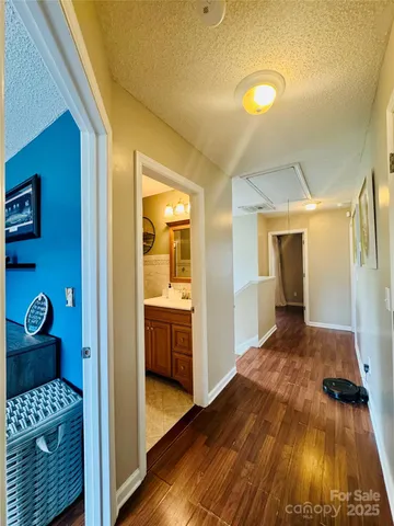 a view of a hallway with wooden floor and bathroom