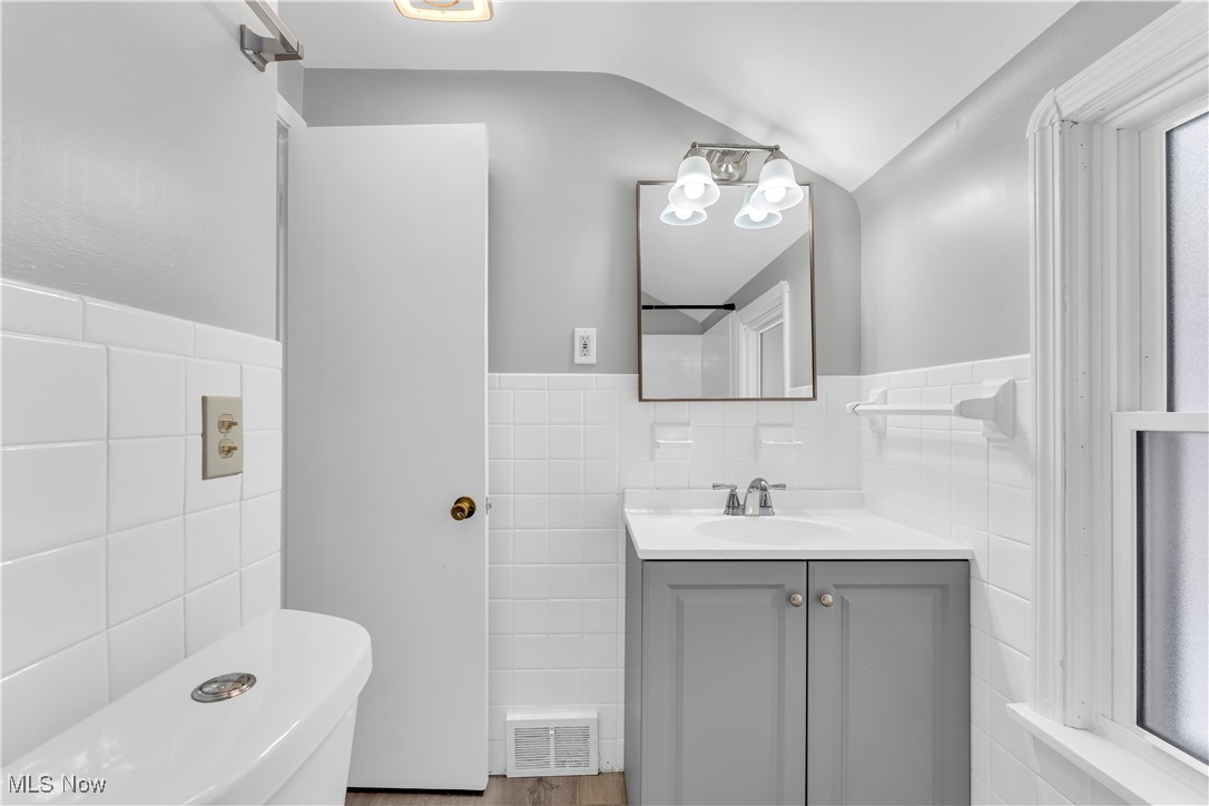 4693 Liberty Road South Euclid, OH 44121 - Photo 24 of 33 Bathroom with vanity, a wainscoted wall, tile walls, and vaulted ceiling