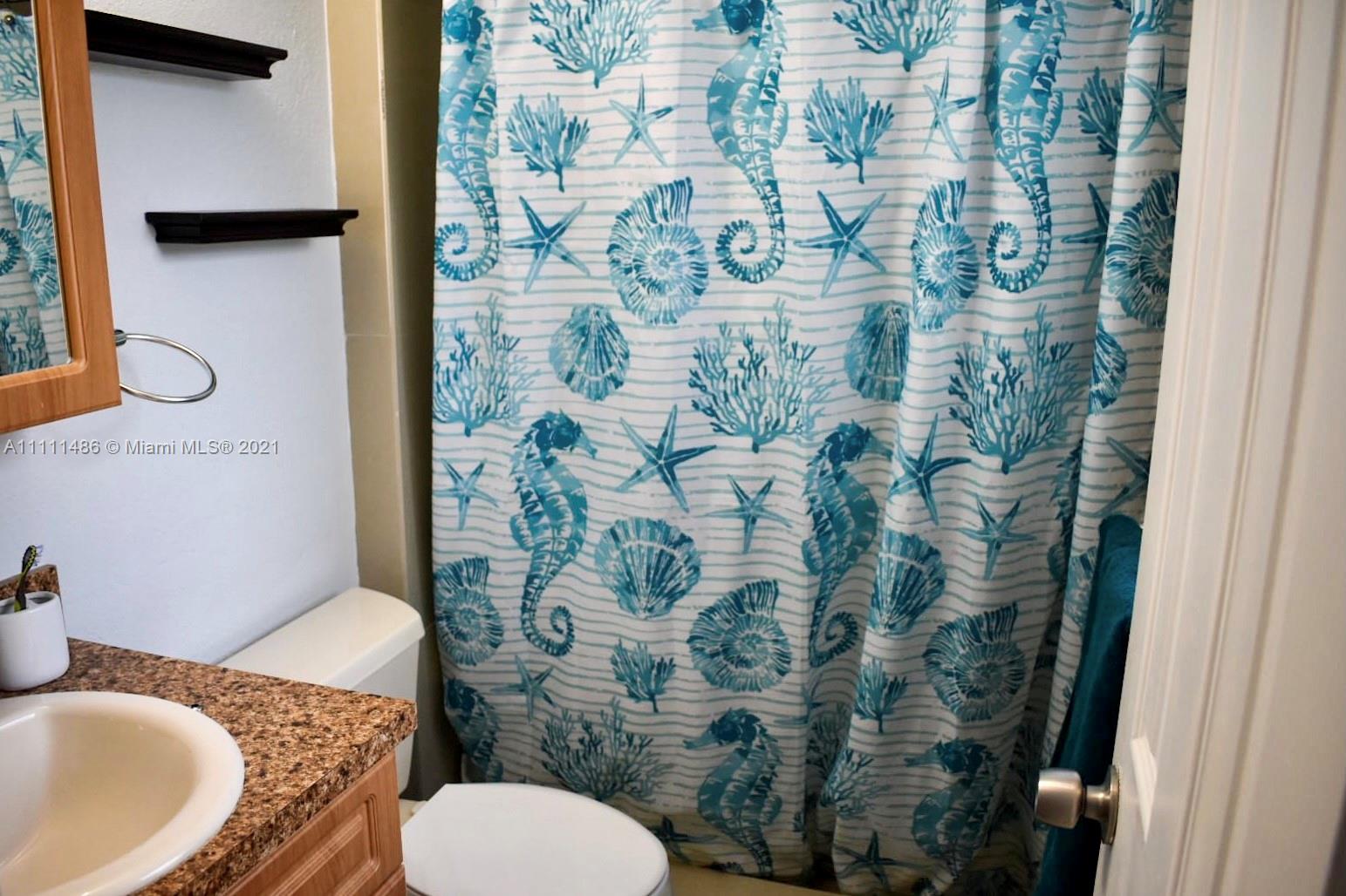 18280 Mediterranean Boulevard, Unit 43 Hialeah, FL 33015 - Photo 18 of 28 a bathroom with a toilet and shower curtain