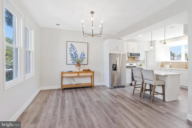 a dining room with wooden floor a chandelier a wooden table and chairs