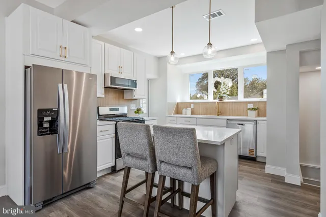 a kitchen with stainless steel appliances granite countertop a dining table chairs refrigerator and cabinets