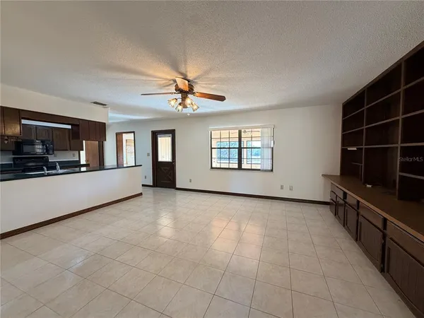 a view of an empty room with wooden floor and a ceiling fan