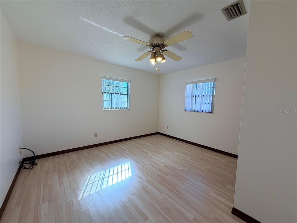 35324 Blanton Road Dade City, FL 33523 - Photo 39 of 49 an empty room with wooden floor chandelier fan and windows