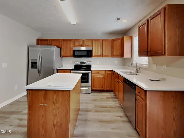 a kitchen with a sink a counter top space cabinets and stainless steel appliances