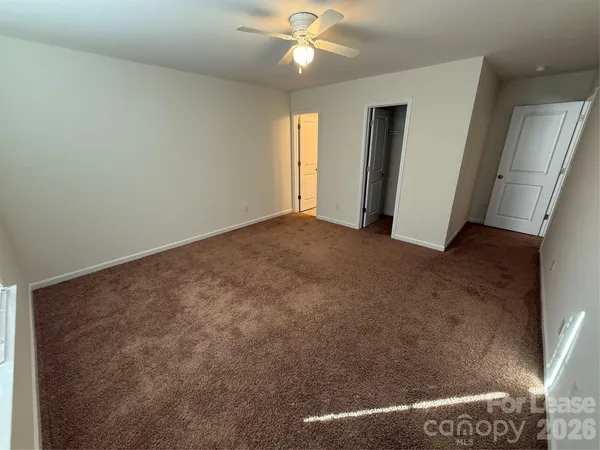 an empty room with closet and a ceiling fan