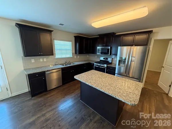 a kitchen with stainless steel appliances kitchen island granite countertop a stove refrigerator and sink