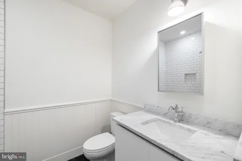 a bathroom with a granite countertop sink toilet and a mirror