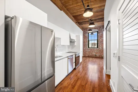 a kitchen with stainless steel appliances granite countertop a refrigerator a stove and a wooden floors