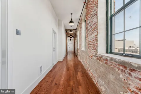 a view of a hallway with wooden floor and a bathroom