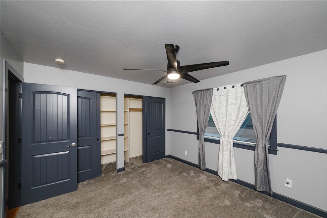 3374 Roma Road Kingman, AZ 86401 - Photo 39 of 64 Unfurnished bedroom with multiple closets, dark colored carpet, and a ceiling fan