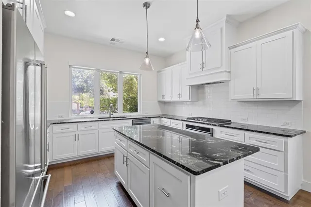 a kitchen with stainless steel appliances granite countertop a sink a stove and a refrigerator