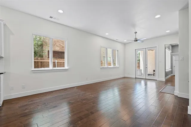 a view of an empty room with wooden floor and windows